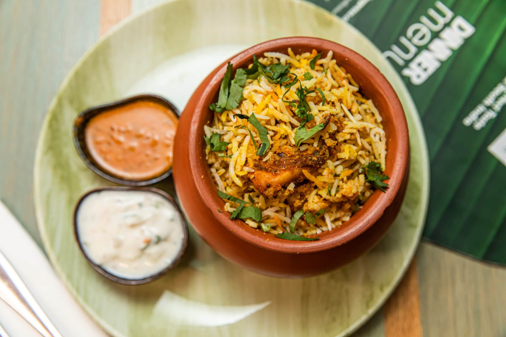 Chicken biryani from Chennai Express, served in a clay matka pot with raita and curry sauce